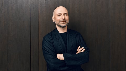 Bald man wearing glasses and a black jacket.