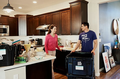 Couple packing moving boxes in a kitchen.