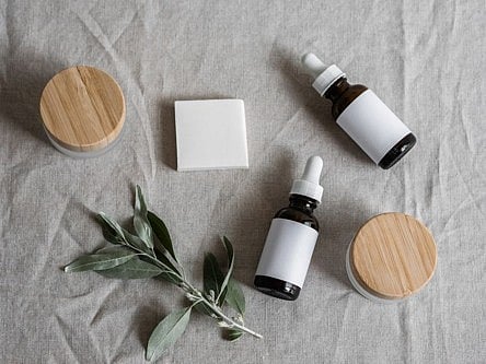 Flat lay of skincare dropper bottles, jars, and plant sprig.