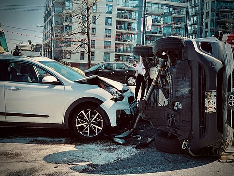 Car accident with an overturned SUV and a damaged white car.