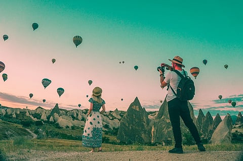 Man photographing a woman watching hot air balloons.