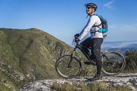 Mountain biker standing on a rocky peak.