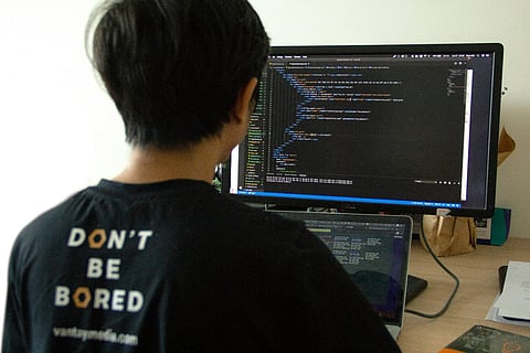 Programmer writing code on dual monitors.