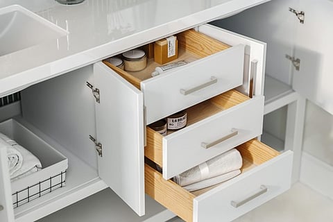 Open drawers of a white bathroom vanity.