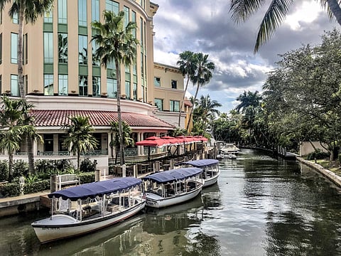 Covered gondola boats docked on a canal beside a terracotta-roofed building with red awnings