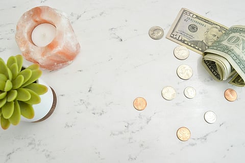 Money, candle, and potted succulent on marble tabletop.