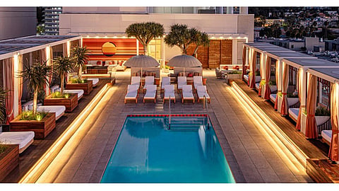 Lit rooftop pool deck with cabanas and lounge seating at W Hollywood at dusk