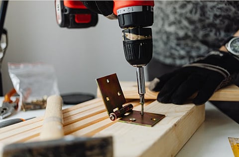 Person drilling a hinge into wood.