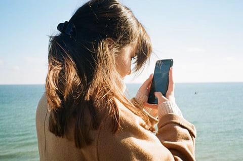 Woman using a smartphone by the ocean.