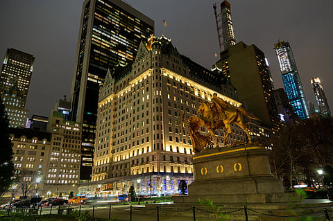 The Plaza Hotel facade lit at night with the gilded Sherman statue in front and towers behind