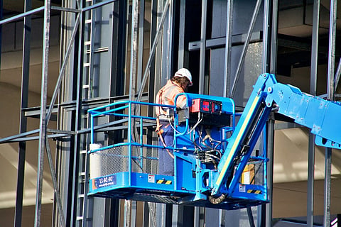 Construction worker in a blue boom lift.