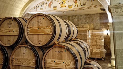 Stacked wine barrels in a stone cellar.   