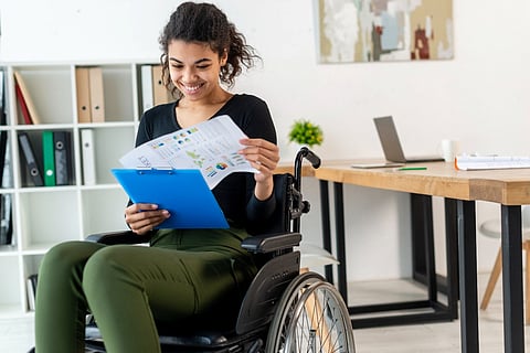 Smiling woman in wheelchair reviewing document.