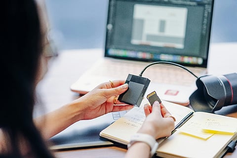 Person holding SD card and reader.