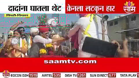 An NCP supporter hangs from a crane to garland Ajit Pawar during a high-voltage roadshow in Pimpri.