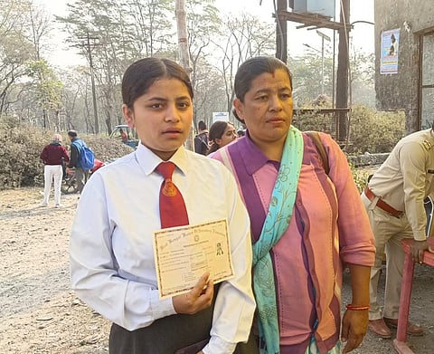 परीक्षा केंद्र के बाहर रजिस्ट्रेशन कार्ड दिखाती छात्रा