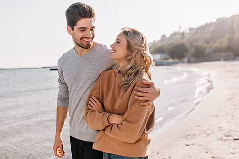 A couple is walking on the sea beach showering love on each other.
