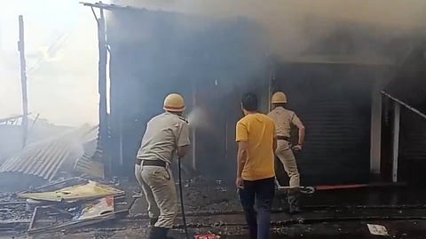 दुकानों में आग बुझाते दमकलकर्मी।