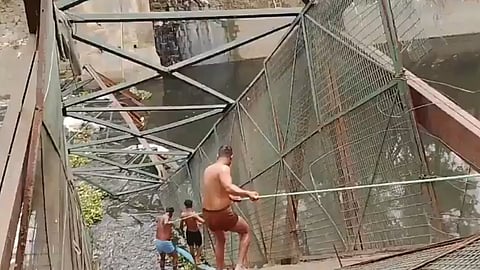 नाले में गिरे हुए फुटओवर ब्रिज से उतर कर बचाव कार्य करते लोग।