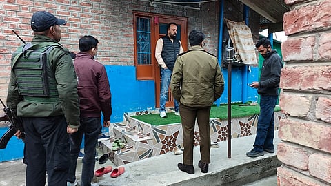 छापेमारी के दौरान एक घर के बाहर पुलिस अधिकारी।