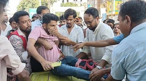 घायल युवक को इलाज के लिए ले जाते लोग
