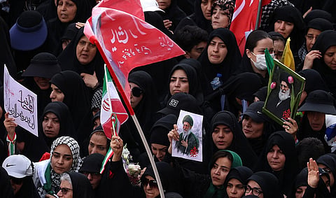 People mourning while holding a picture of the Supreme Leader