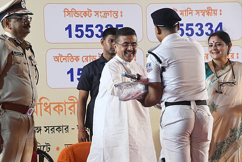 पुलिस कर्मी को मॉनसून किट सौंपते हुए मुख्यमंत्री शुभेंदु अधिकारी