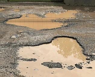 बारिश के बाद सड़क पर जमा पानी और गड्ढा
