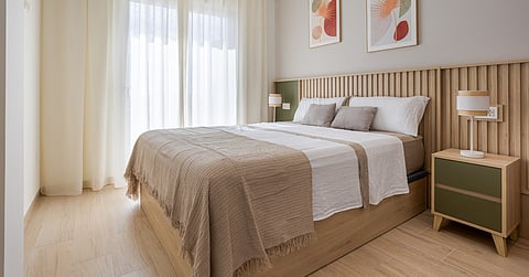 A bedroom with a large bed on a wooden frame, two nightstands with green drawers, and colorful images on the wall.