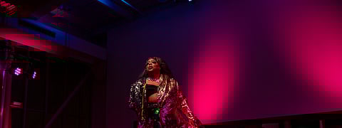 Seattle drag queen Londyn Bradshaw performs "Mt. Everest" by Labyrinth in front of the audience at the ninth annual Legendary Children event. She is wearing sparkly clothing and cast in colorful lighting.