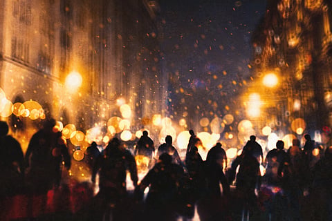 Silhouette of a group of zombies walking through a burning city.
