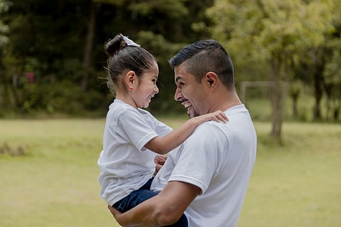 Latine adult man hugging a Latine girl.