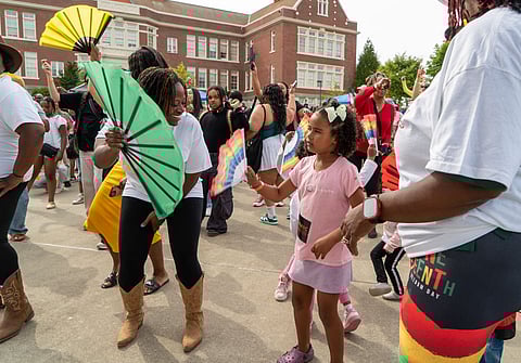 Juneteenth 2025 celebration in Seattle with families and children dancing with rainbow and neon fans in front of a historic building.