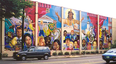 Colorful “Rainbow Valley” mural by Carlos Callejo on the Darigold building in Seattle’s Rainier Valley, depicting multicultural community life, historic landmarks, and diverse residents in vibrant, symbolic scenes.