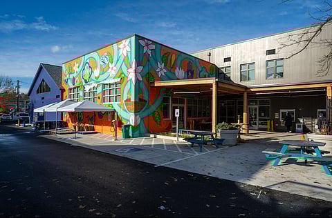 The exterior of the Rainier Valley Food Bank shows a colorful mural with large flowers and tiles.