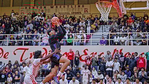 Rainier Beach star Tyran Stokes drives to the basket past Renton defender Samson Mullen for a dunk during a packed high-school game, with fans filling the bleachers as Stokes powers through contact in an 81–60 season-opening win.