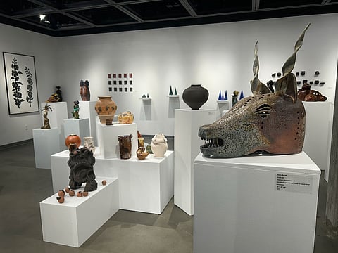A gallery with ceramic art by Black ceramists displayed on pedestals of various heights.