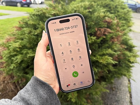 Washington Immigrant Solidarity Network deportation defense hotline number displayed on a smartphone screen outdoors.
