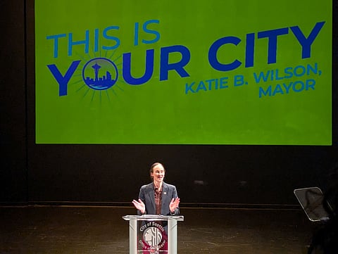 Seattle Mayor Katie Wilson delivers her first State of the City address, standing at a podium with the City of Seattle seal beneath a screen reading “This Is Your City.”