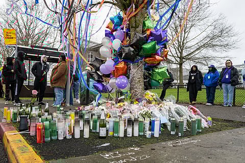 A memorial for two teenagers killed in a shooting at a Rainier Beach bus stop, with many candles and balloons wound around a tree.