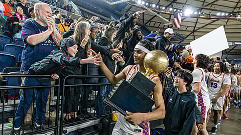 Rainier Beach basketball player Micah Ili-Meneese carries the State Boys 3A trophy and high fives a crowd. 