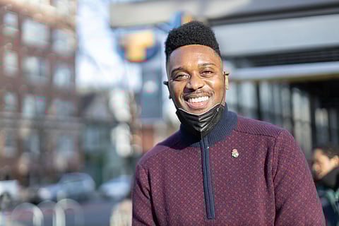 Shaun Scott smiles at the camera with a mask over his chin but pulled down low enough that you can see his smile.