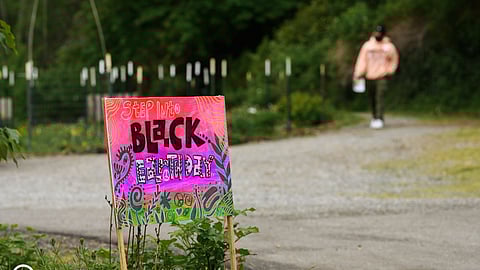 Colorful "Step into Black Earth Day" sign on a park path.