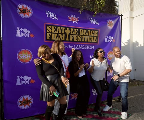 Five Black people stand in front of a banner announcing the Seattle Black Film Festival.
