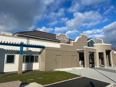 A brown-and-white building sits under a cloudy, blue sky.