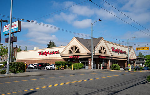 A photo of the Walgreens that will be closing. The sky above is bright blue with white puffy clouds.