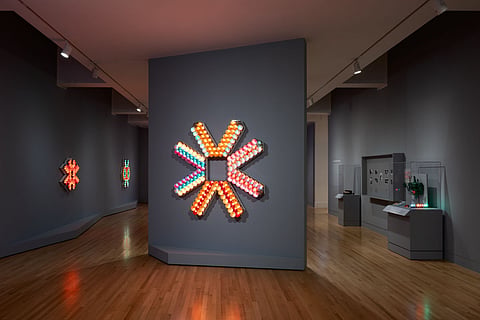 An installation view of "Tom Lloyd," with a large asterisk-shaped light piece at center.