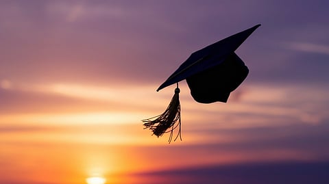 A silhouette of a graduation cap against a background of a sunset.