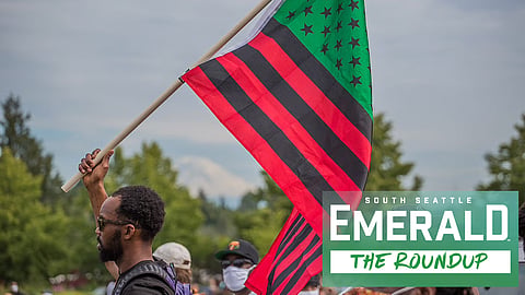 A young man carries a flag as he marches during the Juneteenth celebration at Jimi Hendrix Park on June 19, 2020.