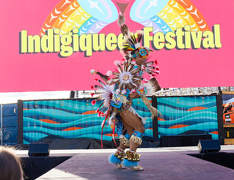 Kellen Lewis performs in traditional regalia on stage.